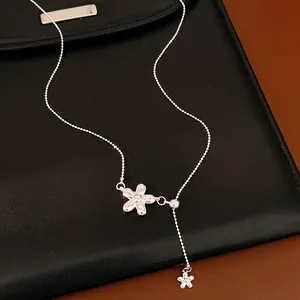 Close-up of silver flower adjustable necklace with elegant metal finish on black background.