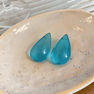 Primo piano dettagliato di orecchini a goccia in resina blu su un piatto di ceramica beige