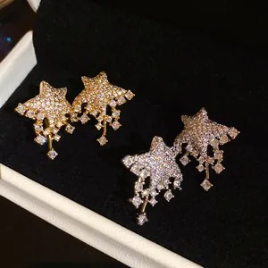 Close-up detail of luxurious silver needle star earrings encrusted with sparkling stones.