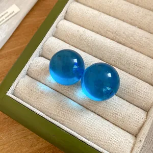 Primo piano di orecchini a lobo in resina blu traslucida in un cofanetto