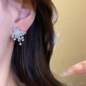 Detail view of sparkling star-shaped crystal stud earrings worn on a model's ear