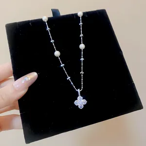 Detailed view of elegant silver flower pendant necklace with pearls and sparkling zircons.