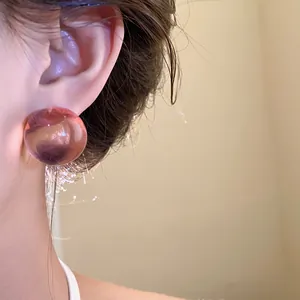 Dettaglio di un orecchino a bottone in resina rosa traslucida in stile minimalista sul modello
