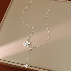 Macro detail of a minimalist silver-tone adjustable Y-chain necklace with flower charms