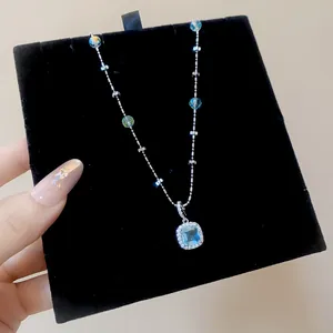 Close-up of elegant silver necklace with blue square zircon pendant on black velvet