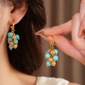 Close-up of elegant 18k gold-plated earrings with blue and gold beads cluster