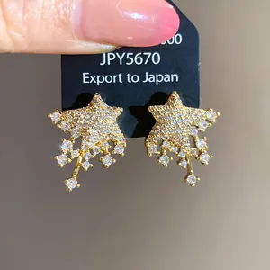 Detailed view of sparkling star-shaped stud earrings with gold finish and zircons.
