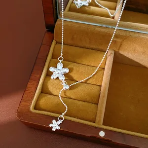 Detailed view of silver flower adjustable Y-necklace in a wooden jewelry box