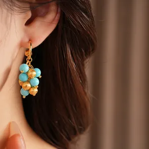 Close-up of elegant gold plated cluster earring with turquoise and textured beads