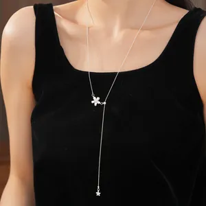 Detail of a minimalist silver flower pull-through necklace on a black velvet top