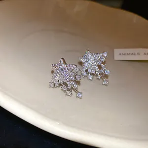 Detail view of silver star stud earrings with brilliant dangling crystals on white dish