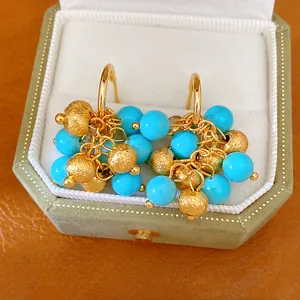 Detailed view of 18k gold plated cluster earrings with blue resin beads in jewelry box