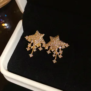 Close-up of gold star stud earrings with sparkling crystals in a black jewelry box