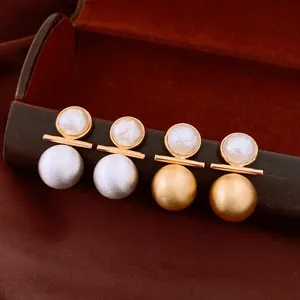 Dettaglio di orecchini a perno in perla placcati oro 18k con metallo spazzolato