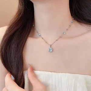 Close-up of elegant geometric light blue zircon pendant necklace worn by a female model
