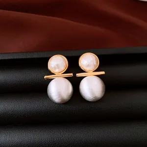 Primo piano di orecchini a perno con perle placcate in oro 18 carati e texture spazzolata