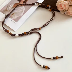 Close-up of bohemian leather cord waist chain with multi-colored wooden beads.