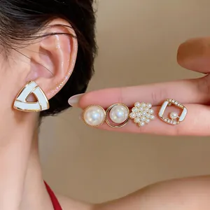 Detail view of French style geometric pearl earrings set with gold finish and rhinestones