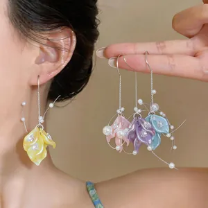 Detailed macro view of colorful flower petal earrings with dangling pearls and zircons.