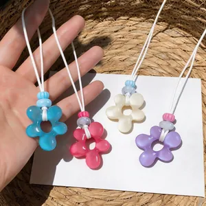 Vue détaillée de pendentifs fleurs en résine colorée avec cordons blancs style plage
