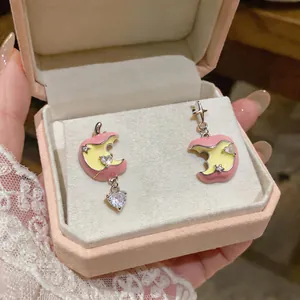 Dettaglio di orecchini rosa a forma di mela morsicata con pendenti cuore in zircone