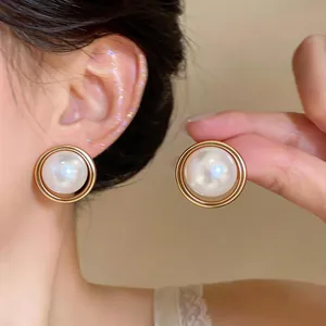 Macro detail of elegant French style pearl stud earrings with gold circular frame