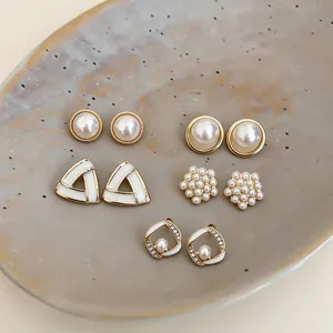 Detailed view of elegant geometric pearl earring set with rhinestones on a ceramic dish