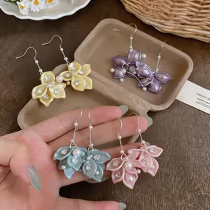 Close-up of elegant floral petal drop earrings with pearls and zircons in multiple colors
