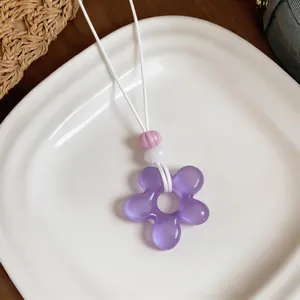Détail d'un pendentif fleur en résine violette pour les tenues de vacances d'été