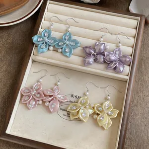 Detailed view of four colorful floral earrings with pearls displayed in a jewelry box