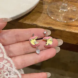 Dettaglio di orecchini mela rosa con zircone a cuore e ciondoli a stella