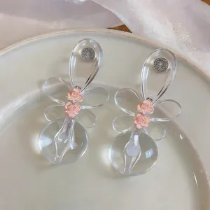 Primer plano detallado de pendientes de resina transparente con pequeñas rosas rosas