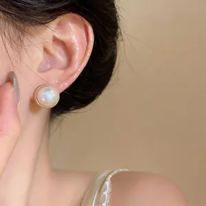 Elegant French style pearl stud earrings with gold beaded border shown on ear
