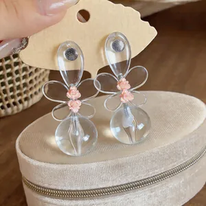 Primer plano de pendientes de flor de resina con centro floral rosa y pétalos transparentes