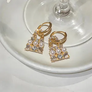 Dettaglio di eleganti orecchini di perle a forma di borsa con cristalli lucidi