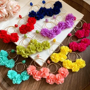 Detailed view of multiple colorful chiffon flower hoop earrings displayed on a vintage book