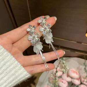 Detailed close-up of silver floral tassel earrings with white petal accents