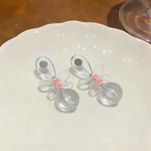 Detalle de pendientes de flores de resina con diseño de lazo y detalles de rosas rosas