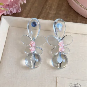 Primer plano de pendientes de mariposa en resina con delicadas rosas rosas
