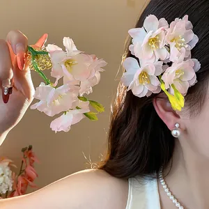 Vista dettagliata delle mollette per capelli a fiori di ciliegio rosa indossate da una modella.