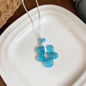 Collier pendentif fleur en résine bleue avec cordon blanc pour style vacances.