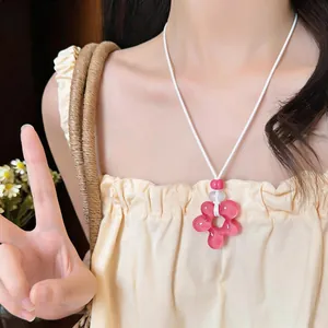 Gros plan d'un collier fleur en résine rose avec cordon en cuir blanc porté par un mannequin