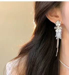Detailed close-up of elegant silver flower petal tassel earrings worn by a model for a luxury look.