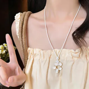 Gros plan d'un modèle portant un collier de fleurs en résine blanche avec cordon en cuir.
