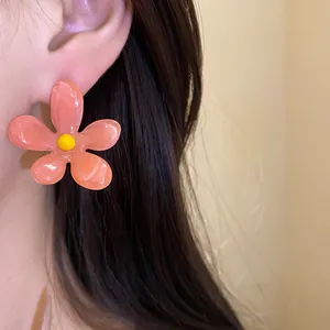 Detailed view of a vibrant pink resin flower earring worn on an ear with dark hair