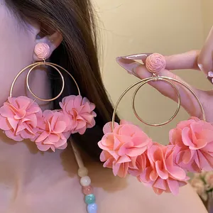 Close-up of pink chiffon flower hoop earrings featuring elegant double golden rings detail.