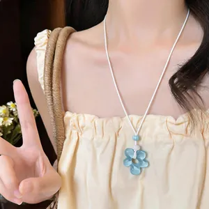 Détail d'un collier pendentif fleur en résine bleu clair sur cordon blanc, mannequin asiatique