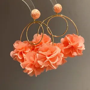 Detailed view of oversized hoop earrings featuring coral chiffon flowers and raffia buds