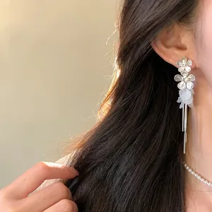 Detailed side view of elegant silver flower petal tassel earrings worn by a model