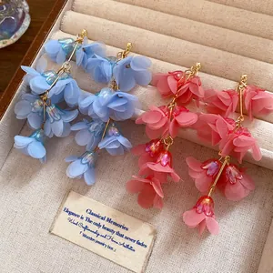 Close-up detail of bohemian fabric flower drop earrings in vibrant blue and pink colors